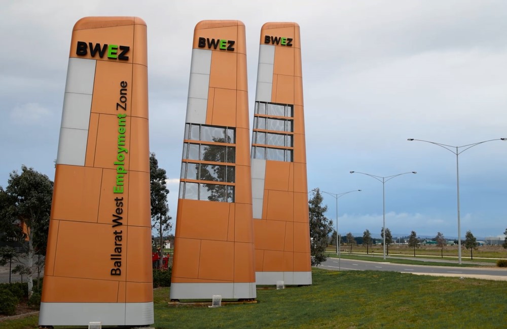 Three tall, aeroplane tail-like signs with BWEZ branding on the side of a road with paddocks in the background.